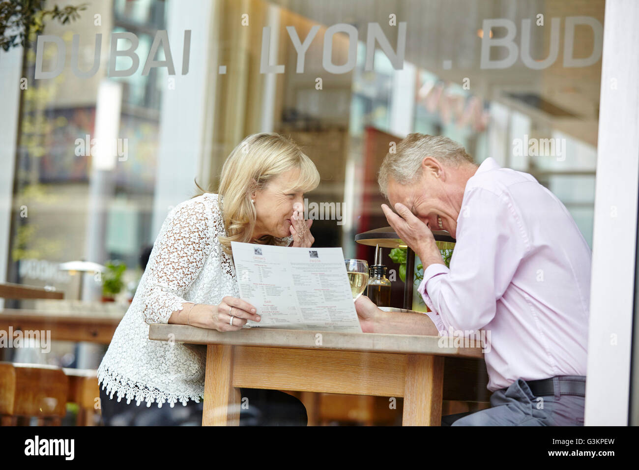 Mature dating couple giggling at restaurant table Stock Photo