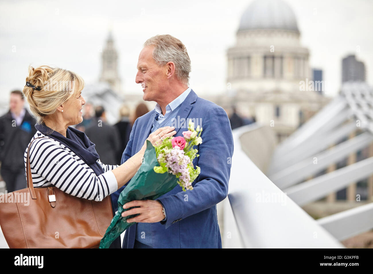 Romantic mature dating couple greeting each other on Millennium Bridge, London, UK Stock Photo