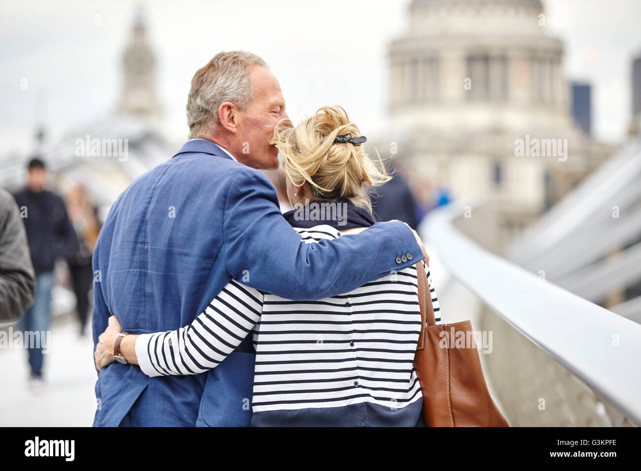 Rear view of romantic mature dating couple crossing Millennium Bridge, London, UK Stock Photo