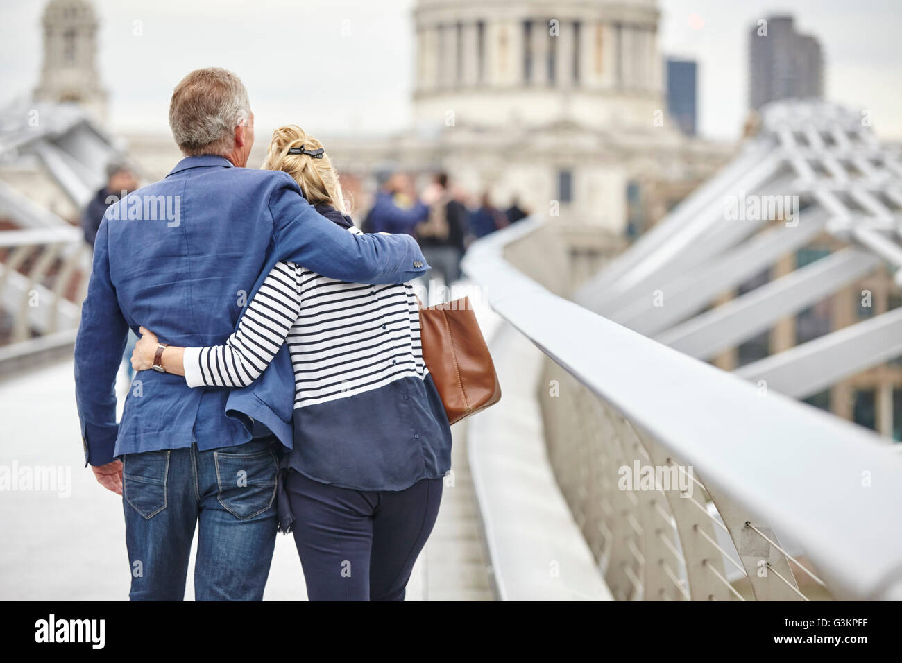 Rear view of mature dating couple  crossing Millennium Bridge, London, UK Stock Photo