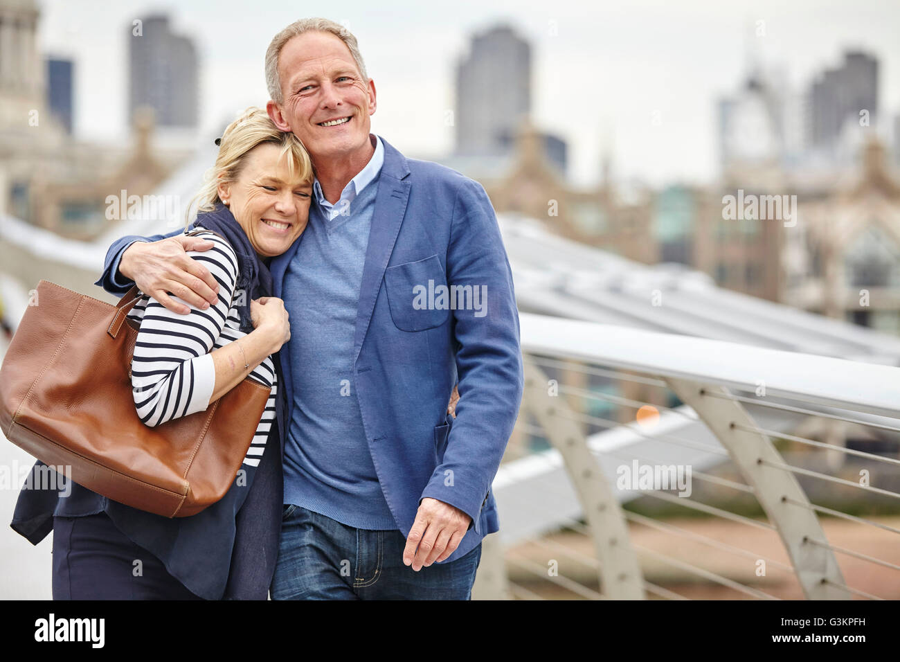 Mature dating couple strolling across Millennium Bridge, London, UK Stock Photo