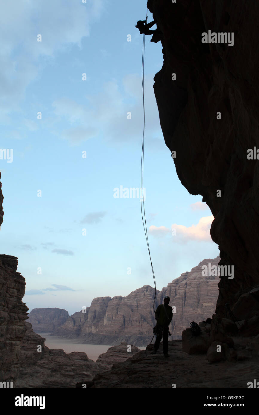 Two silhouetted people rappelling down rock face, Wadi Rum, Jordan Stock Photo Alamy