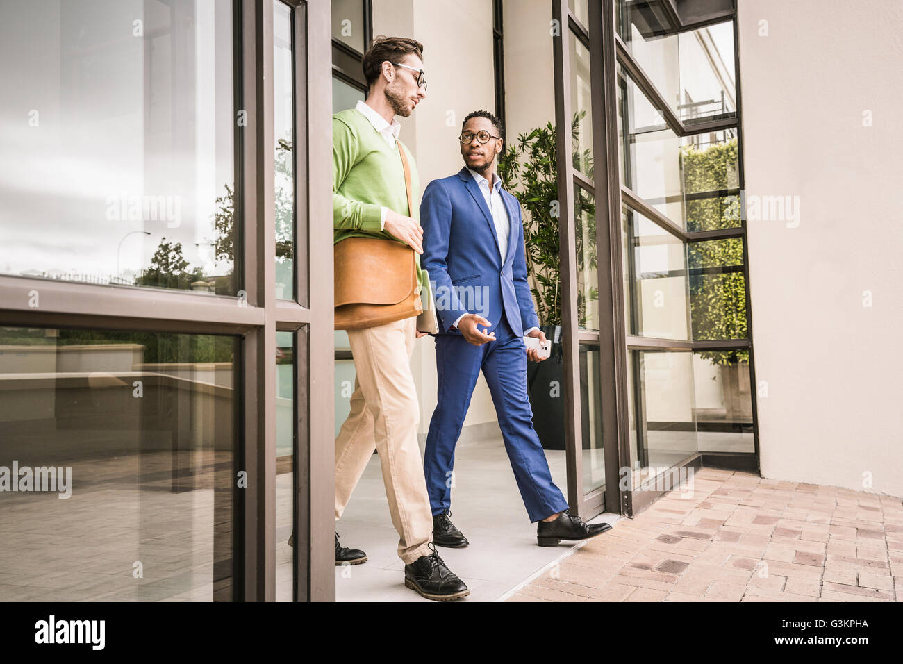 Two businessmen having discussion whilst leaving office building Stock