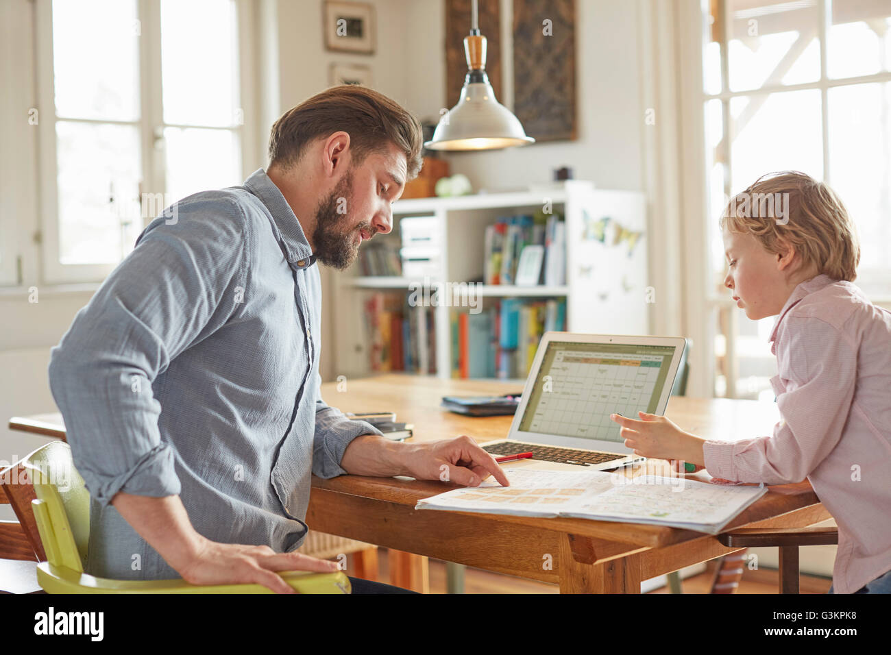 Father helping son with homework in home office Stock Photo