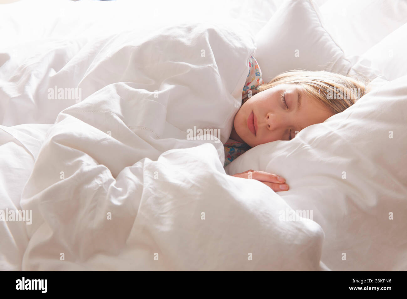 Blond haired girl asleep in bed Stock Photo
