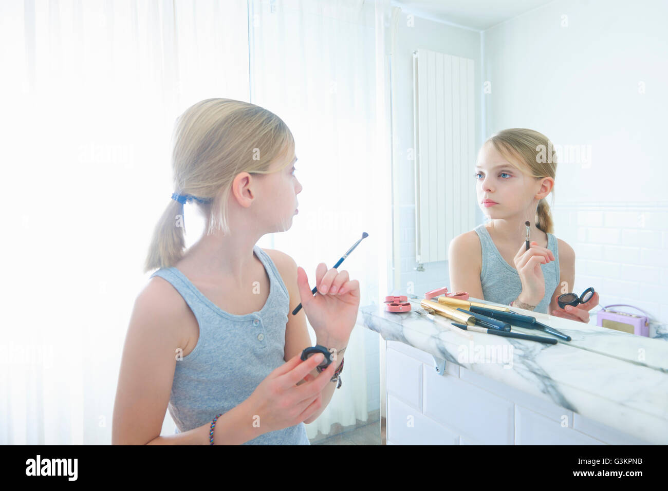 Bedroom mirror image of girl with make up brush staring at herself Stock Photo