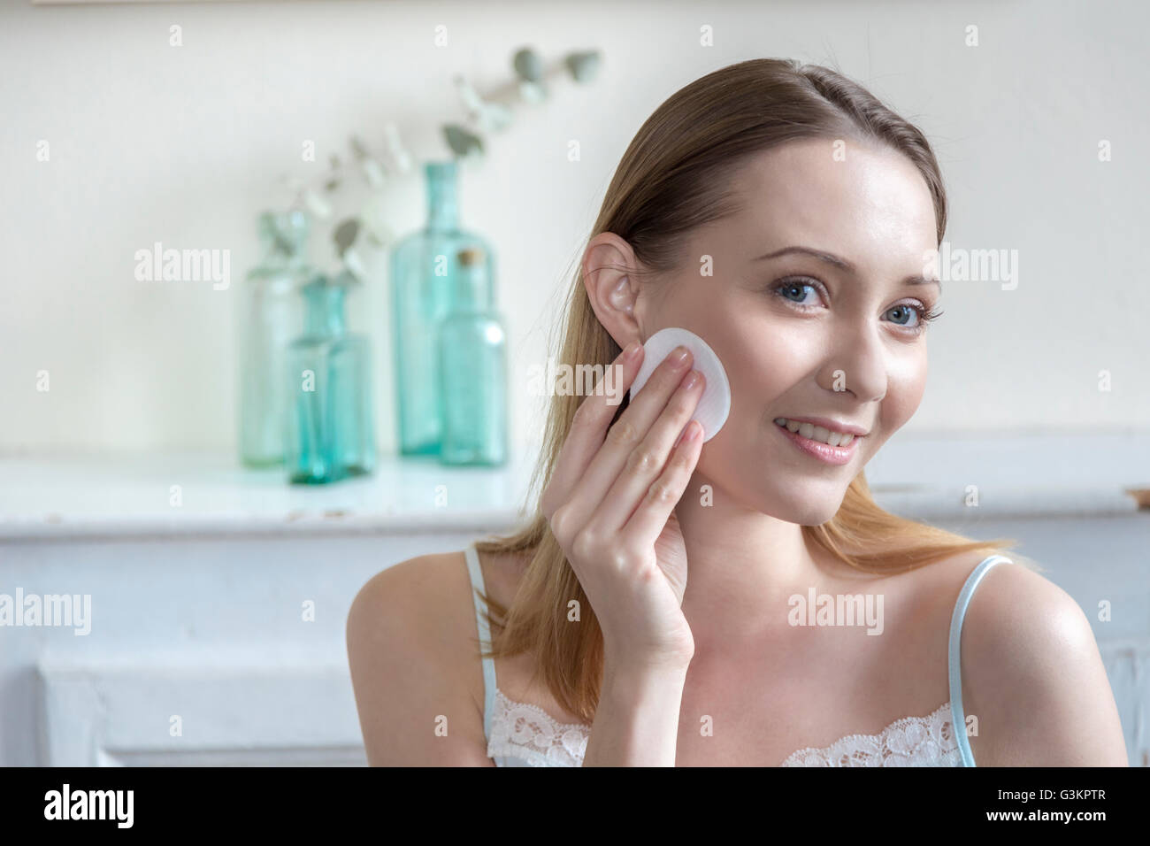 Woman moisturising face with cotton wool pad Stock Photo