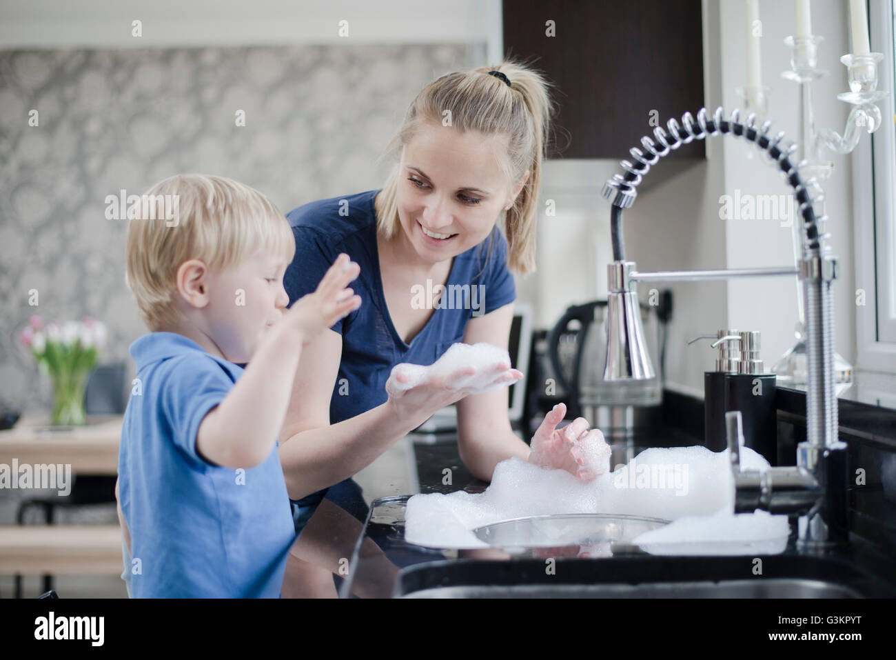 Mother and son doing washing up together Stock Photo