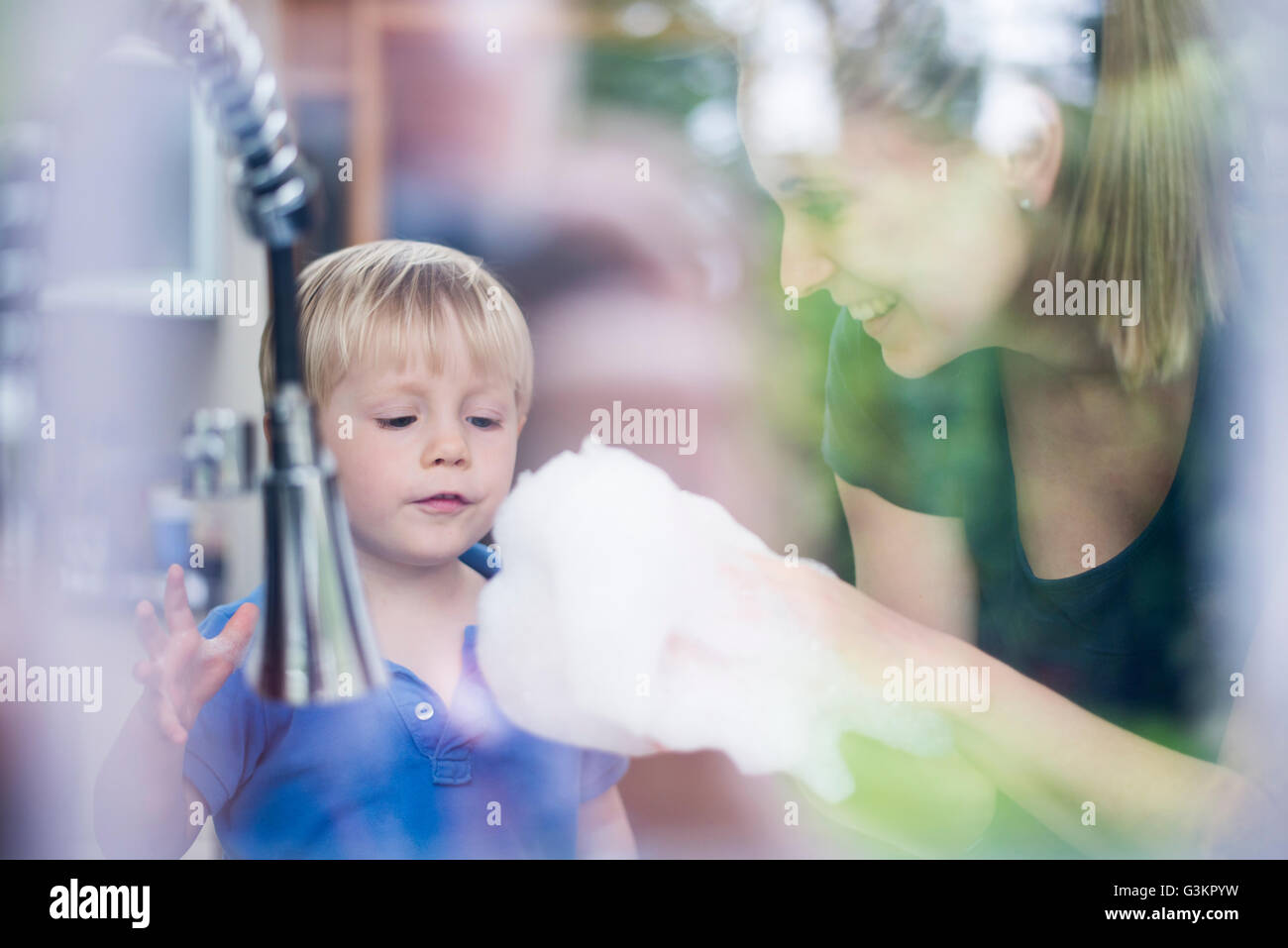 Mother and son doing washing up together, playing with bubbles Stock Photo