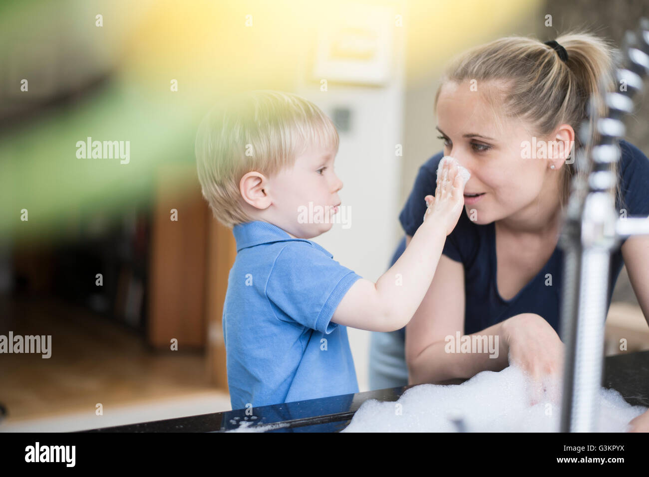 Mother and son doing washing up together, playing with bubbles Stock Photo