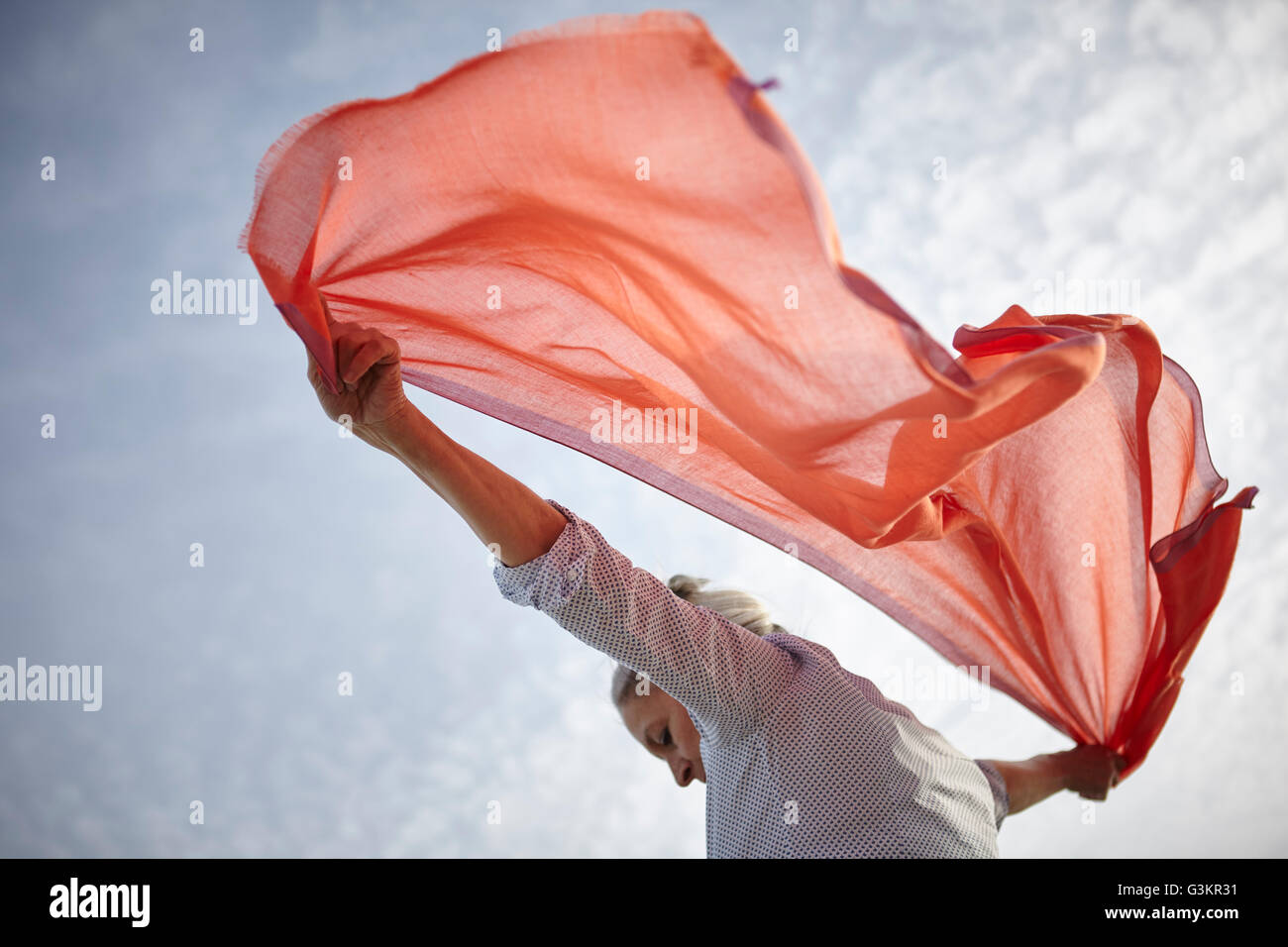 Mature woman outdoors, holding scarf behind her, low angle view Stock Photo