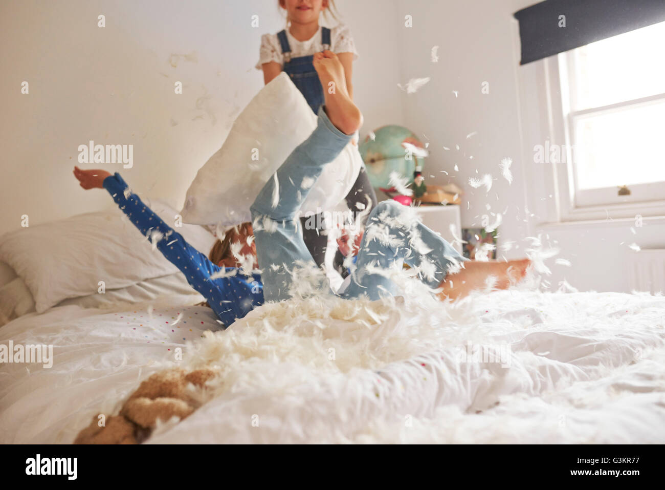 Two sister having feather pillow fight on bed Stock Photo