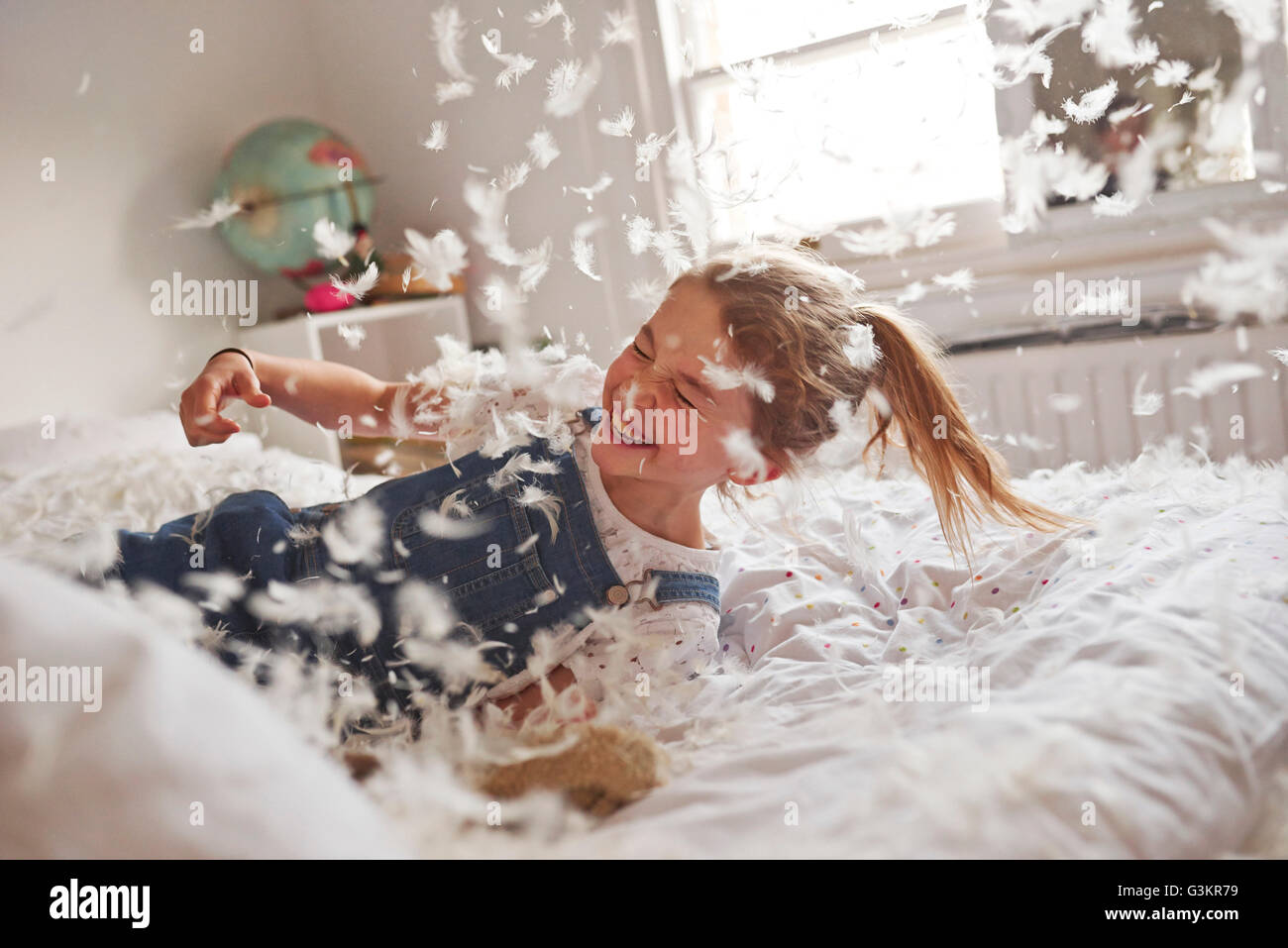 Girl falling on feather pillow fight bed Stock Photo