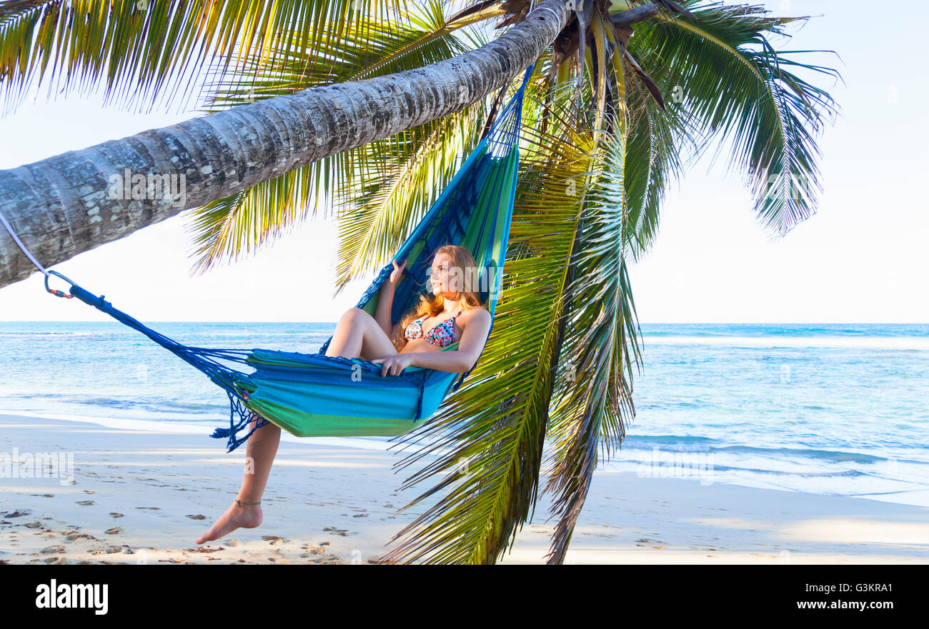 Young woman reclining in palm tree hammock, Dominican Republic, The