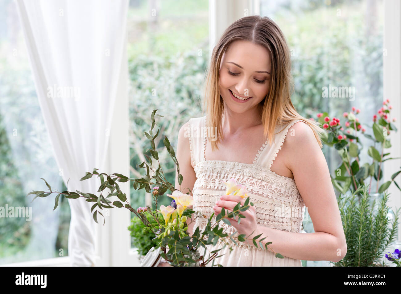 Woman arranging flowers looking down smiling Stock Photo
