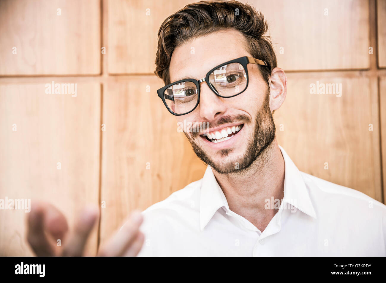 Young man wearing glasses looking at camera smiling, gesticulating Stock Photo
