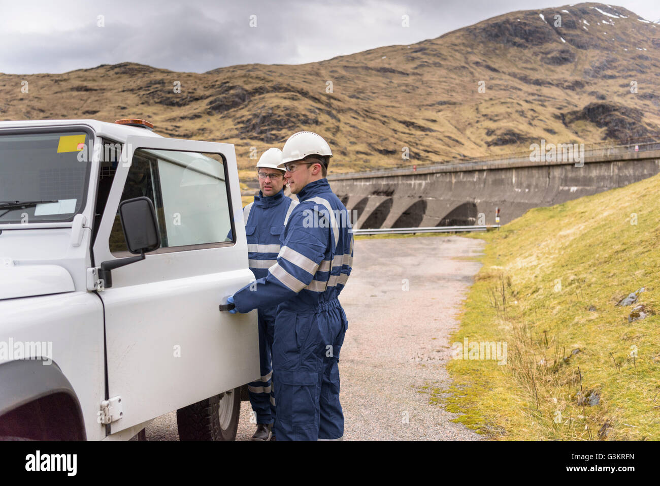 Workers with utility vehicle by dam at hydroelectric power station Stock Photo