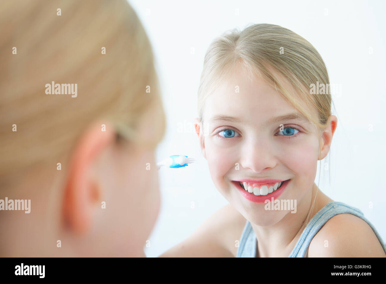 Bathroom mirror portrait of girl holding toothbrush Stock Photo