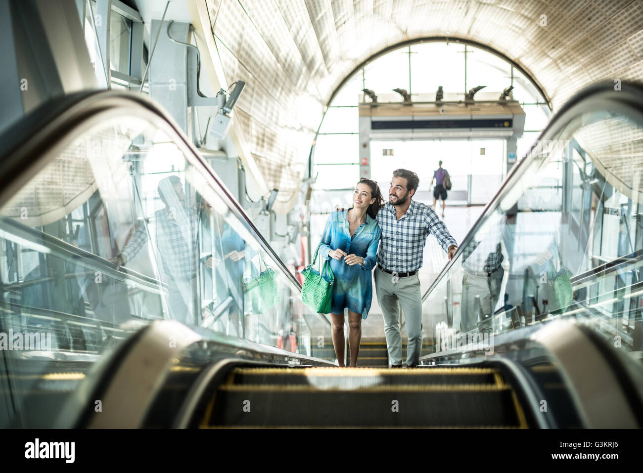 Tourist couple moving up escalator in shopping mall, Dubai, United Arab Emirates Stock Photo