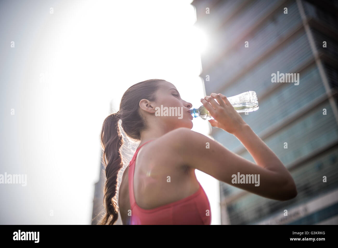 Woman training, drinking bottled water in park, Dubai, United Arab Emirates Stock Photo