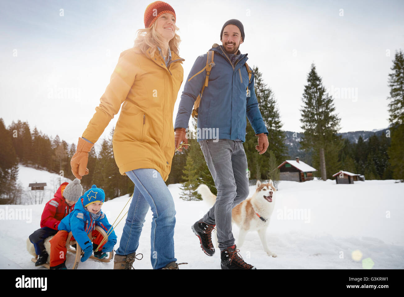 Parents pulling sons on toboggan in winter landscape, Elmau, Bavaria