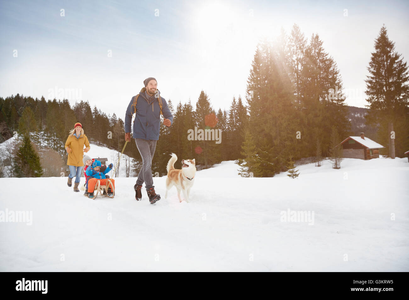 Parents pulling sons on toboggan in snow covered landscape, Elmau, Bavaria, Germany Stock Photo