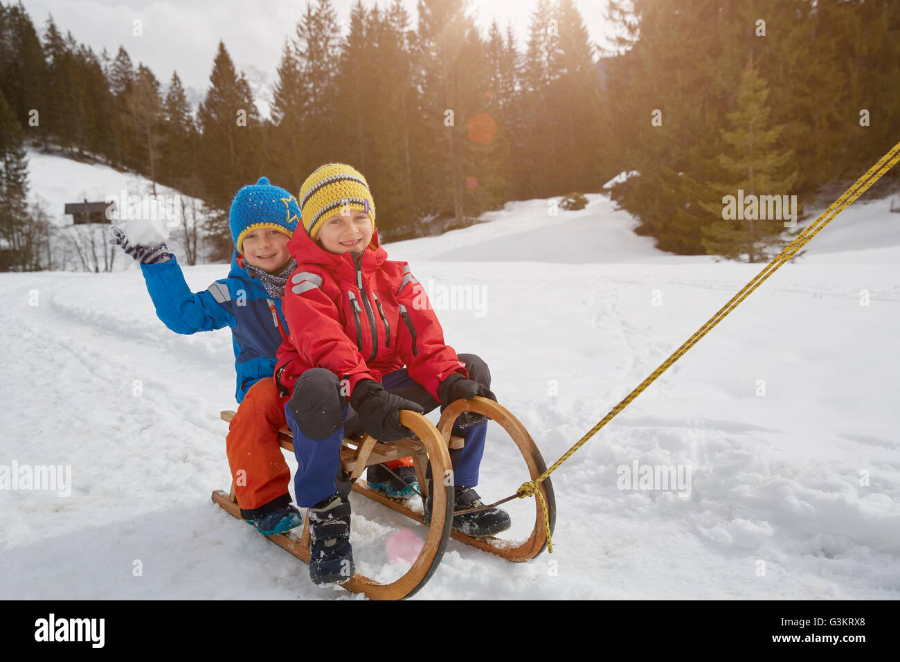 Boy and brother being pulled on toboggan in snow, Elmau, Bavaria, Germany Stock Photo