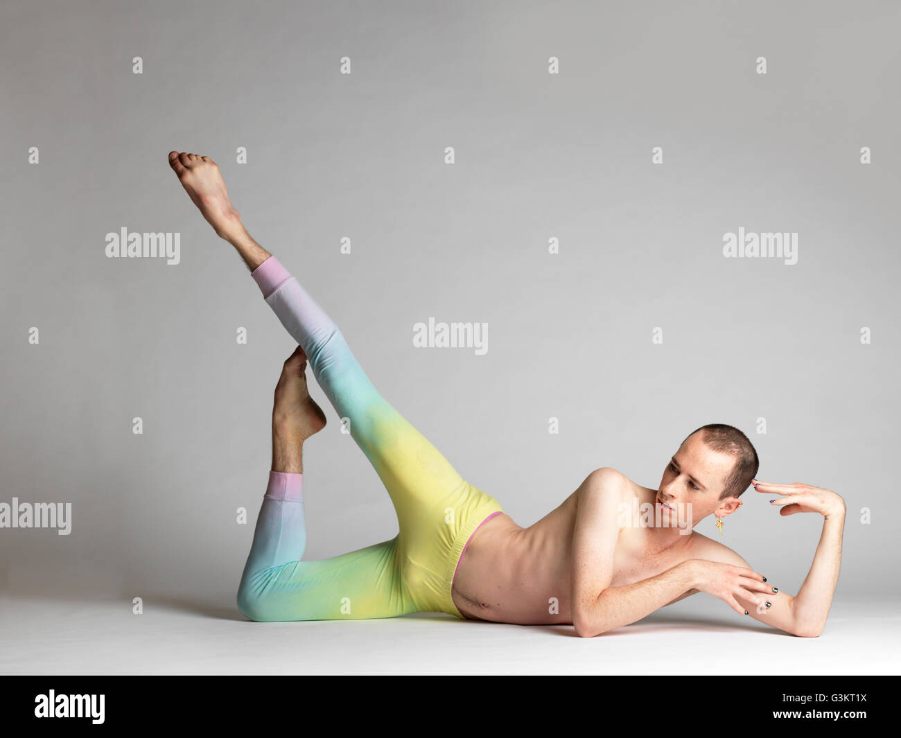 Young male dancer wearing multi- coloured leggings poised on studio floor Stock Photo