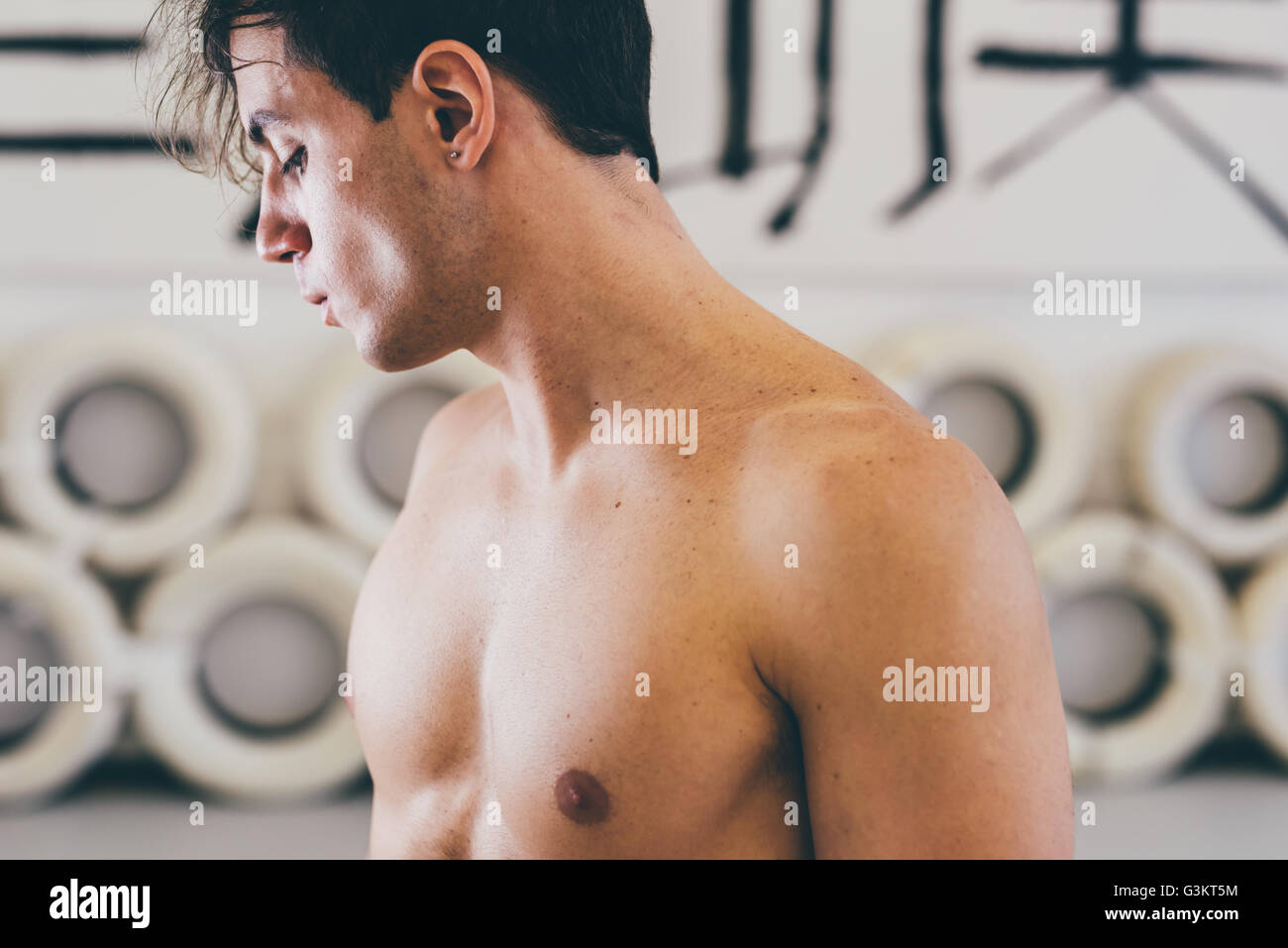 Bare chested man in gym looking away Stock Photo