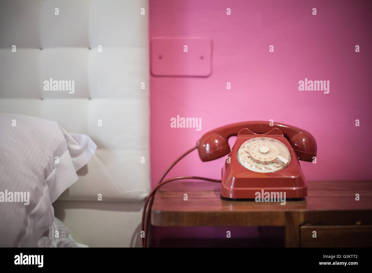 Red rotary telephone on bedside table Stock Photo