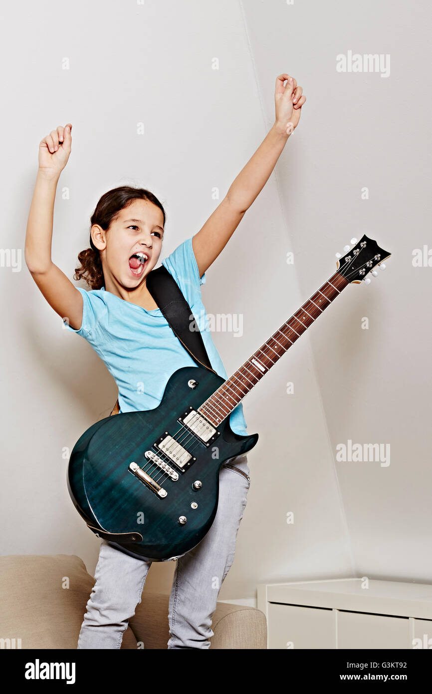 Girl with guitar, mouth open, arms raised in triumph Stock Photo Alamy