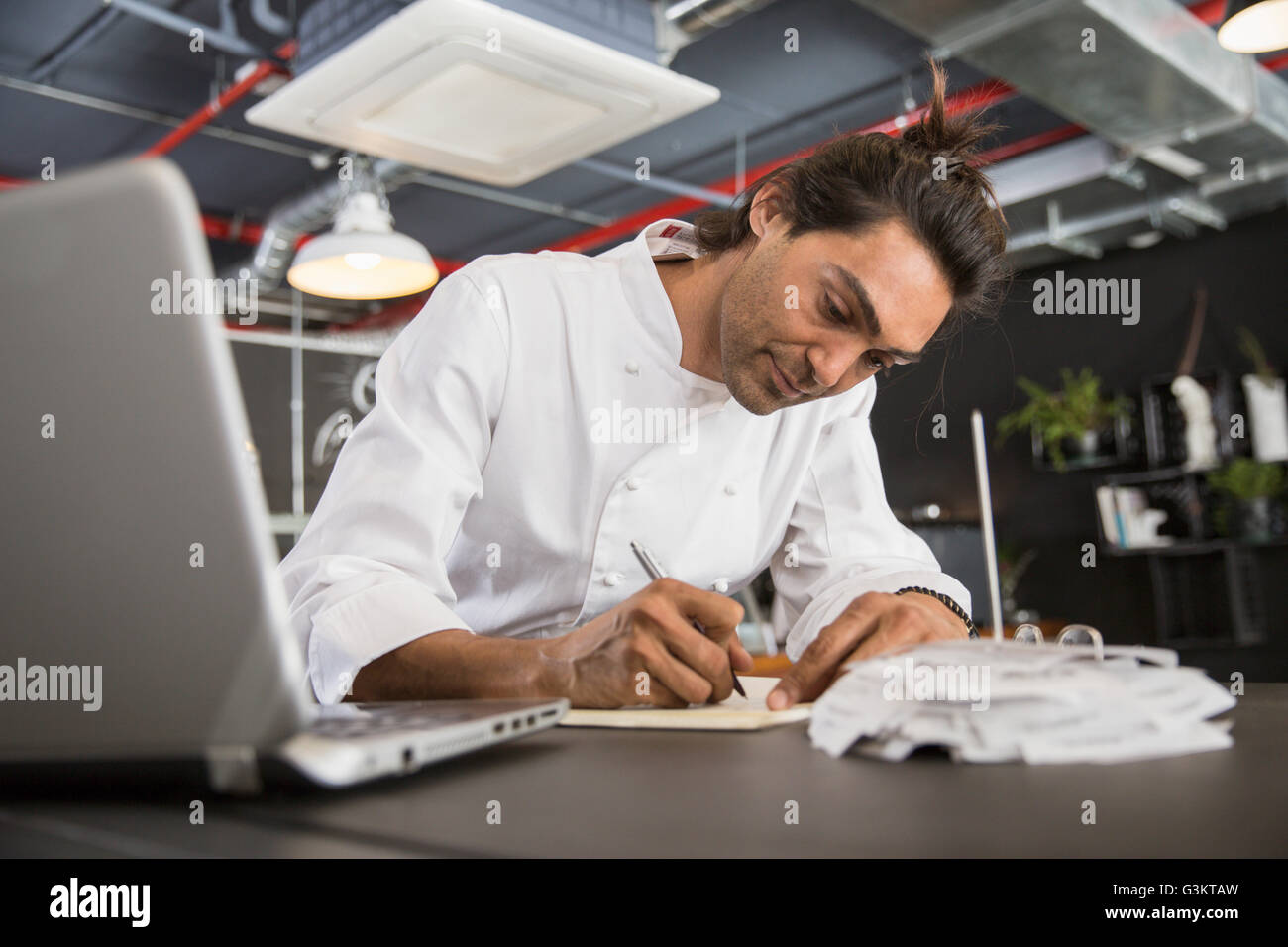 Chef in restaurant writing in notepad Stock Photo