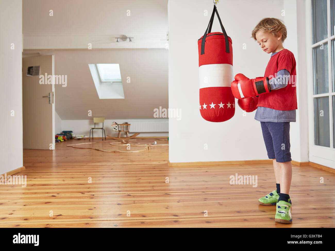 Boy with punch bag putting on boxing gloves Stock Photo