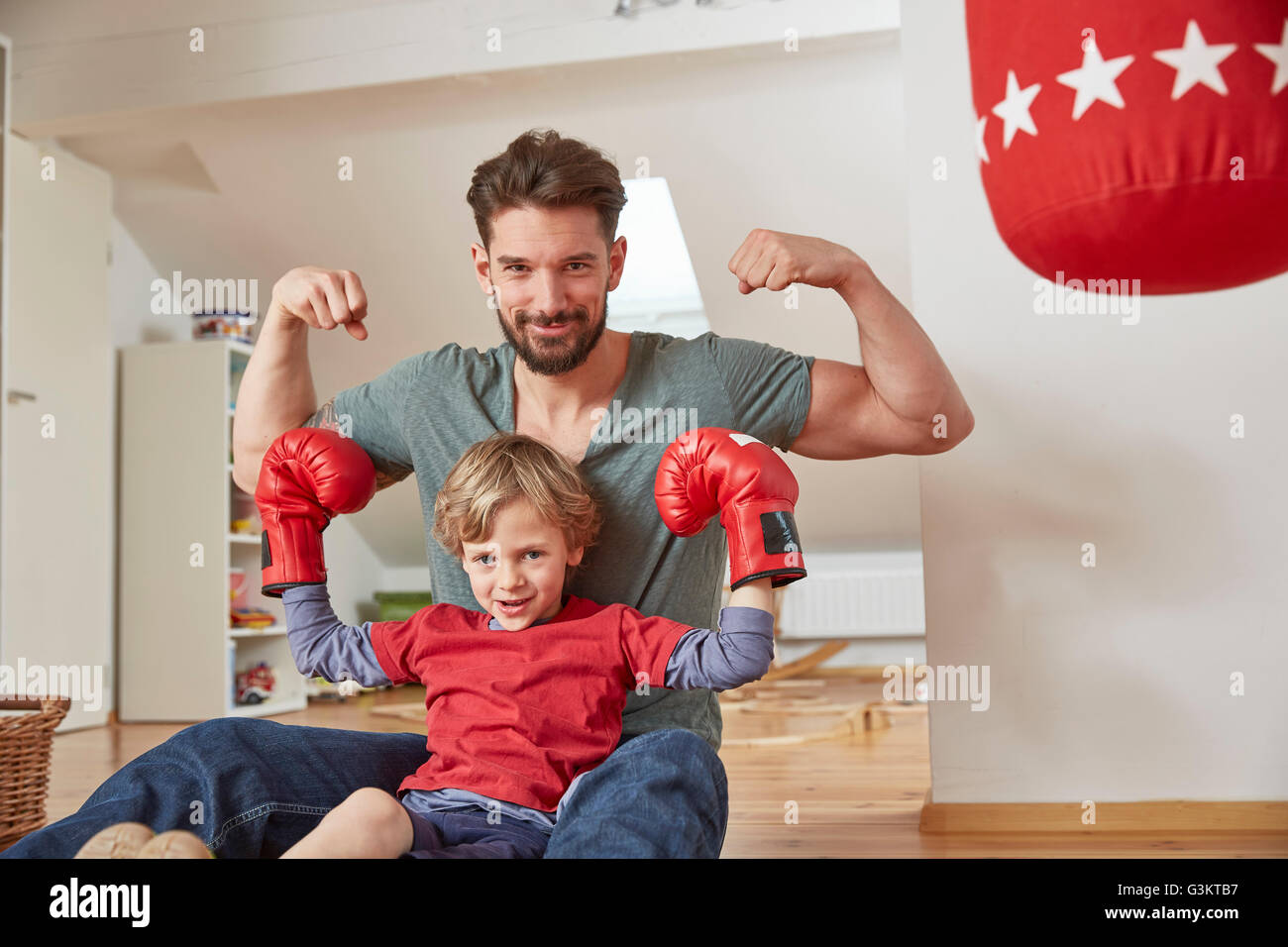 Boy wearing boxing with father, flexing muscles looking at camera Stock Photo
