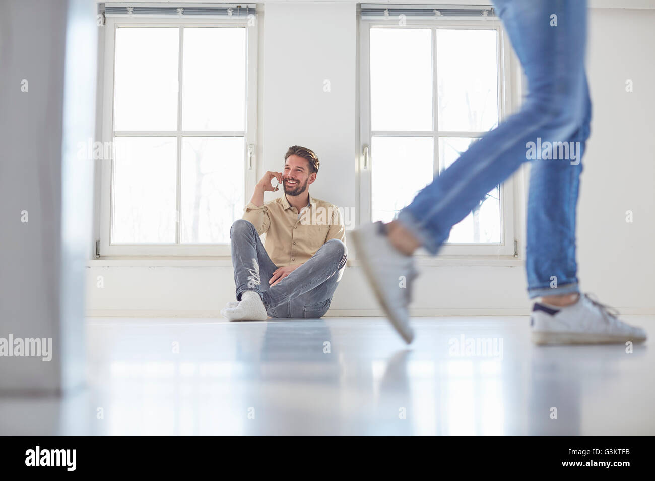 Man sitting on floor talking on smartphone in new home Stock Photo