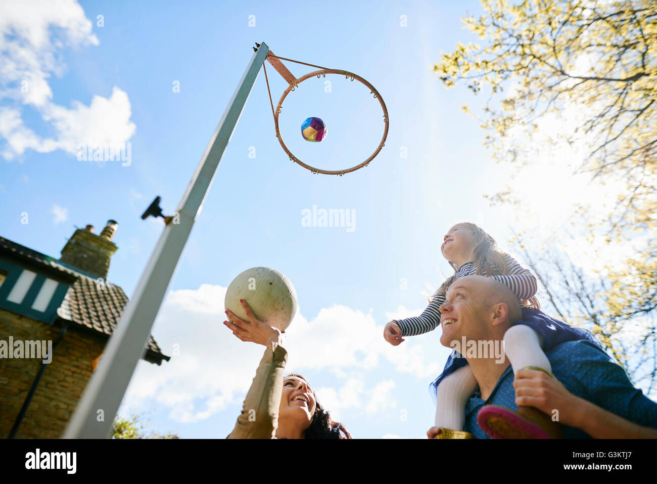 Family throwing basketball through basketball hoop Stock Photo