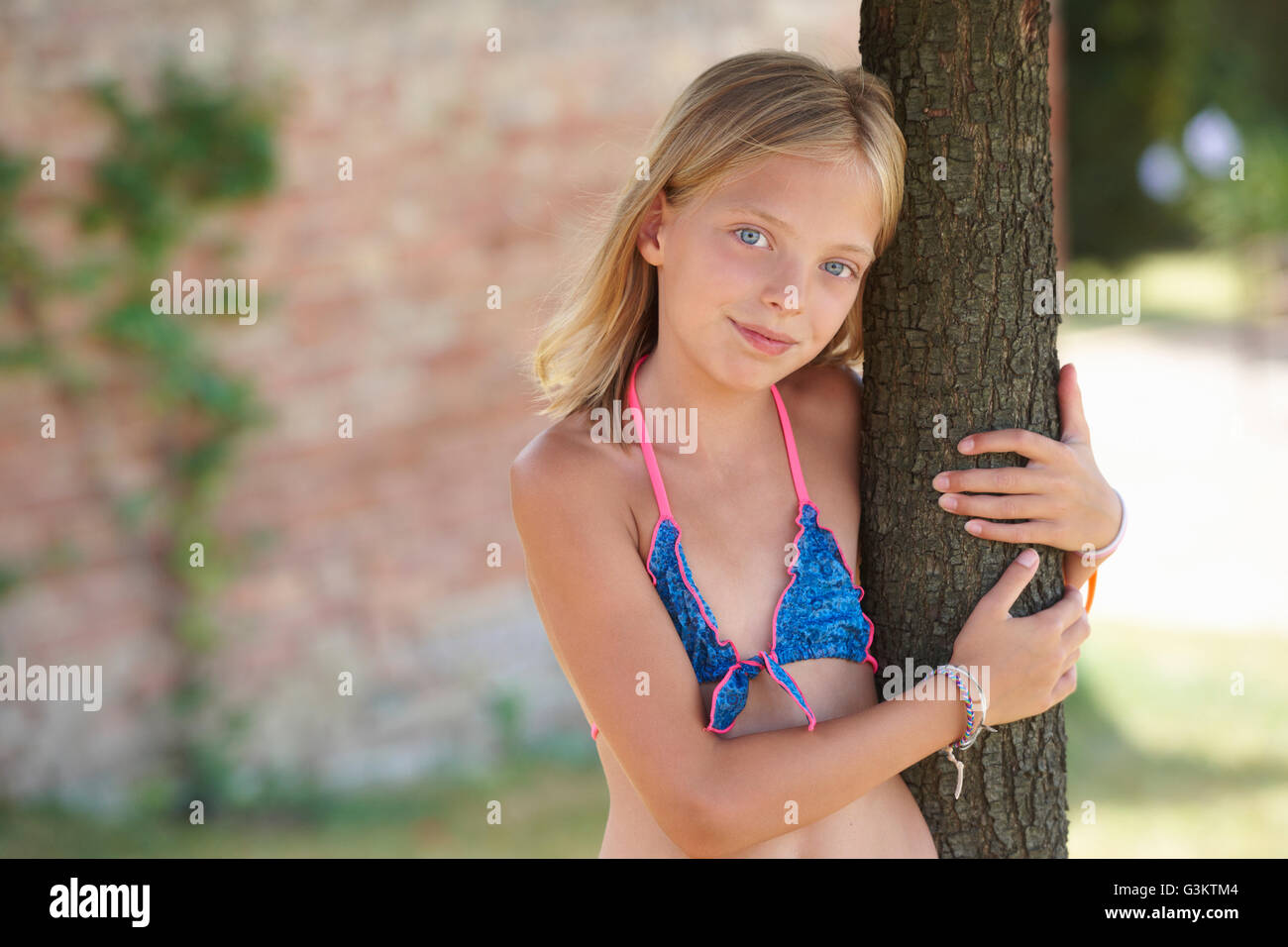 Portrait of girl wearing bikini top leaning against tree, Buonconvento, Tuscany, Italy Stock Photo