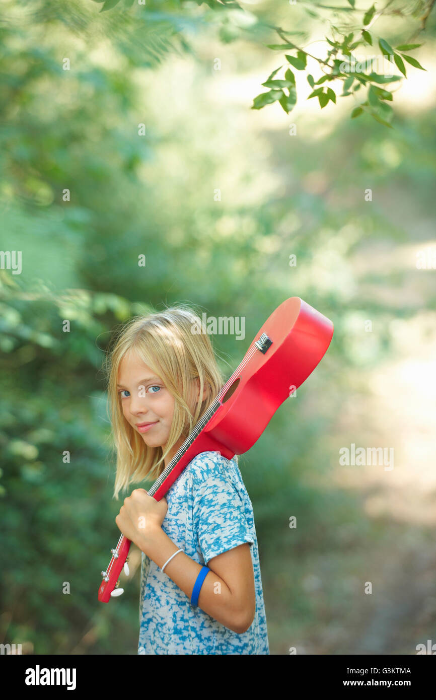 Portrait of girl with red ukulele in woodland, Buonconvento, Tuscany, Italy Stock Photo