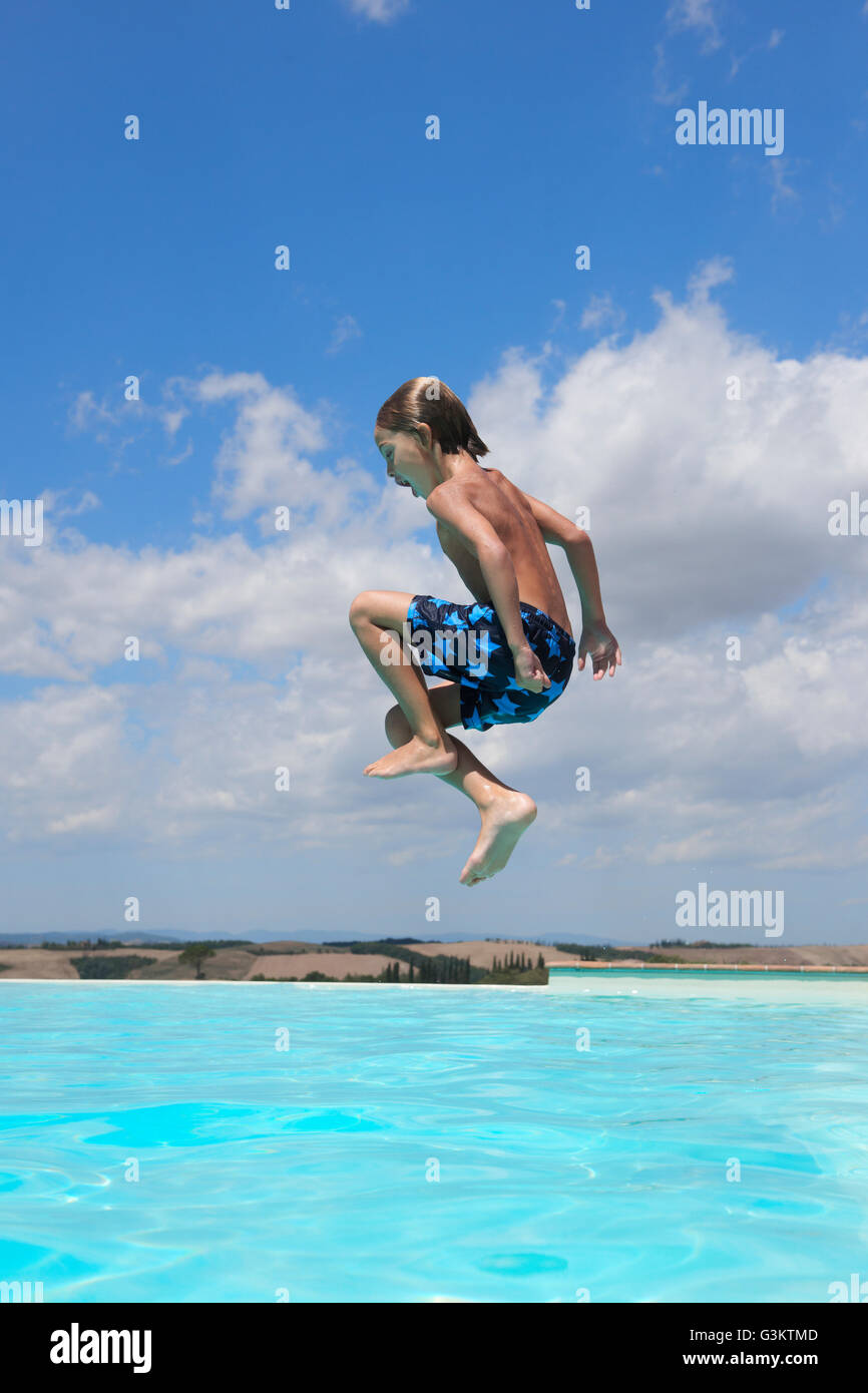 Boy jumping into swimming pool, Buonconvento, Tuscany, Italy Stock Photo