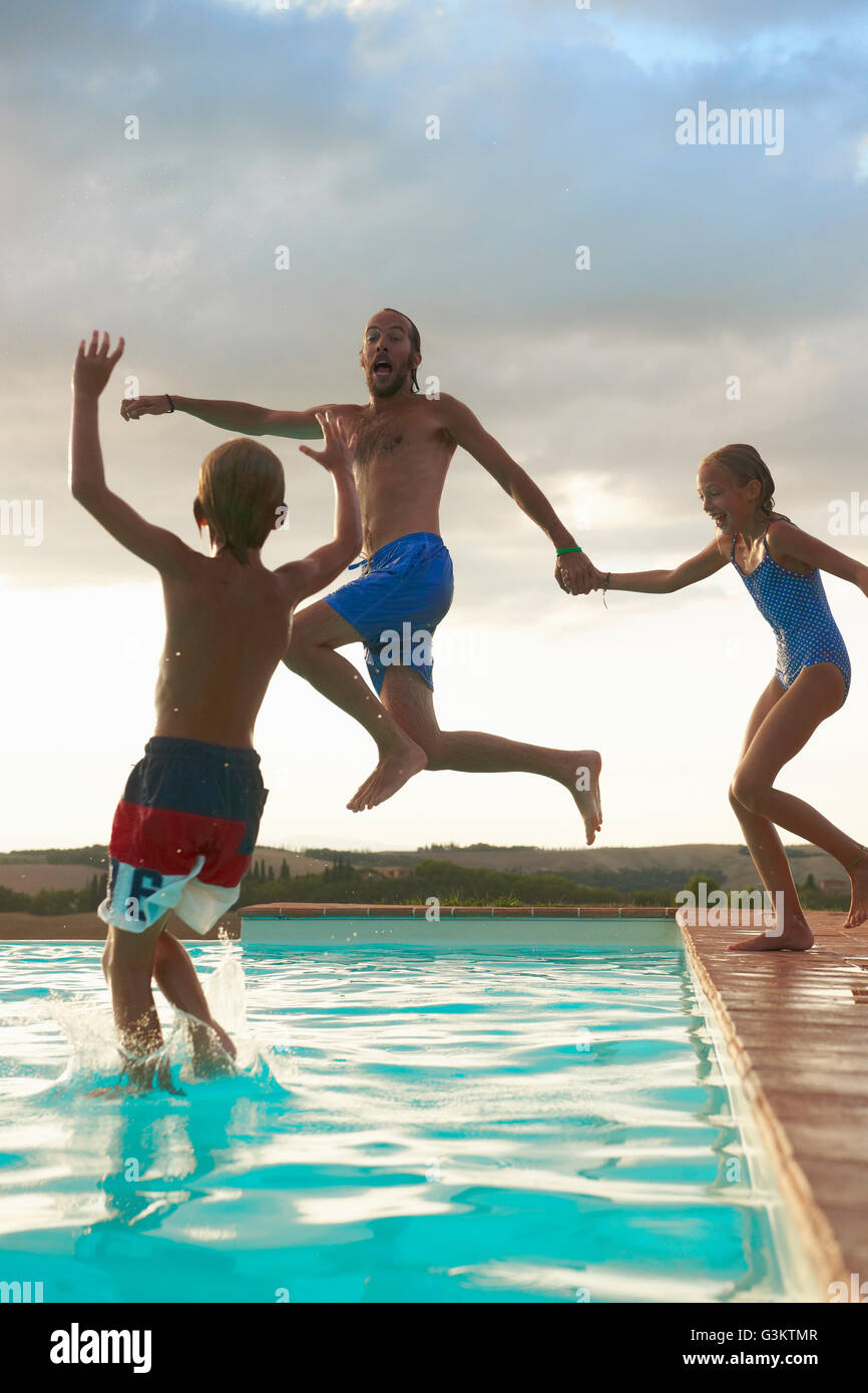Man jumping into swimming pool with daughter and son, Buonconvento, Tuscany, Italy Stock Photo