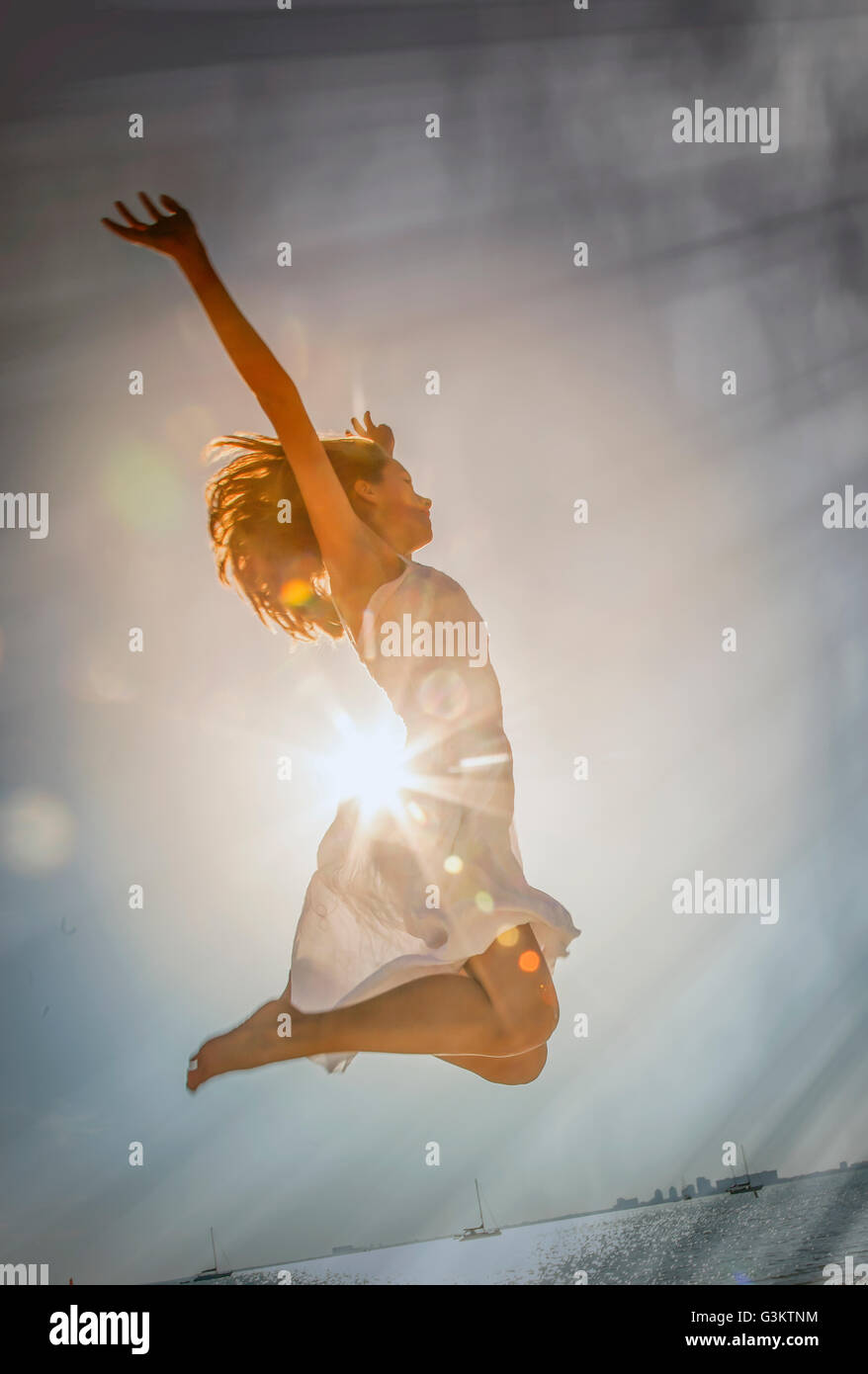 Young woman jumping mid air at sunset on Miami Beach, Florida, USA Stock Photo