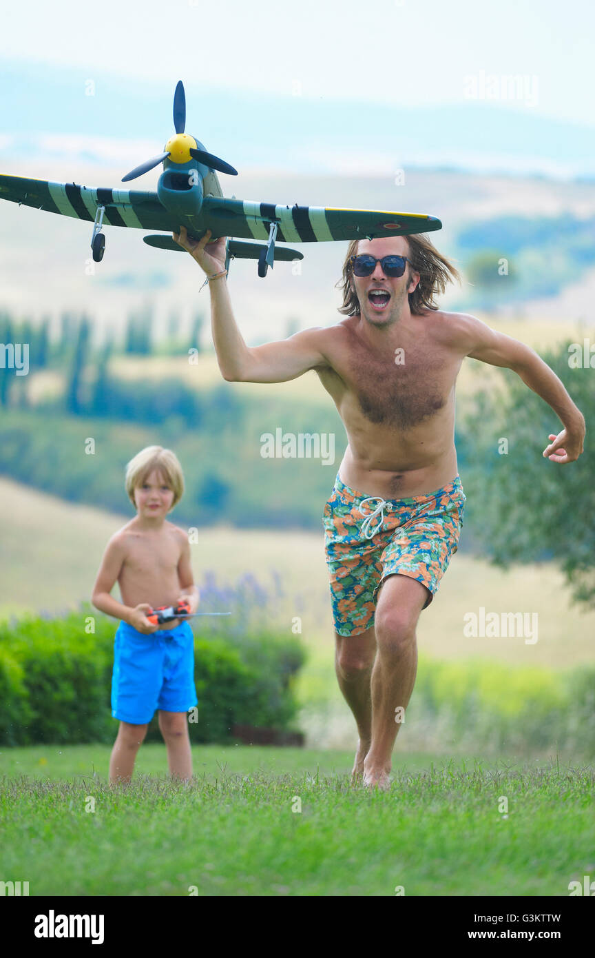Father and son flying remote control plane, outdoors Stock Photo