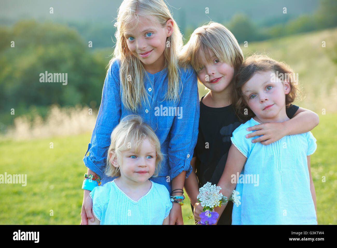 Portrait of four siblings standing in field Stock Photo