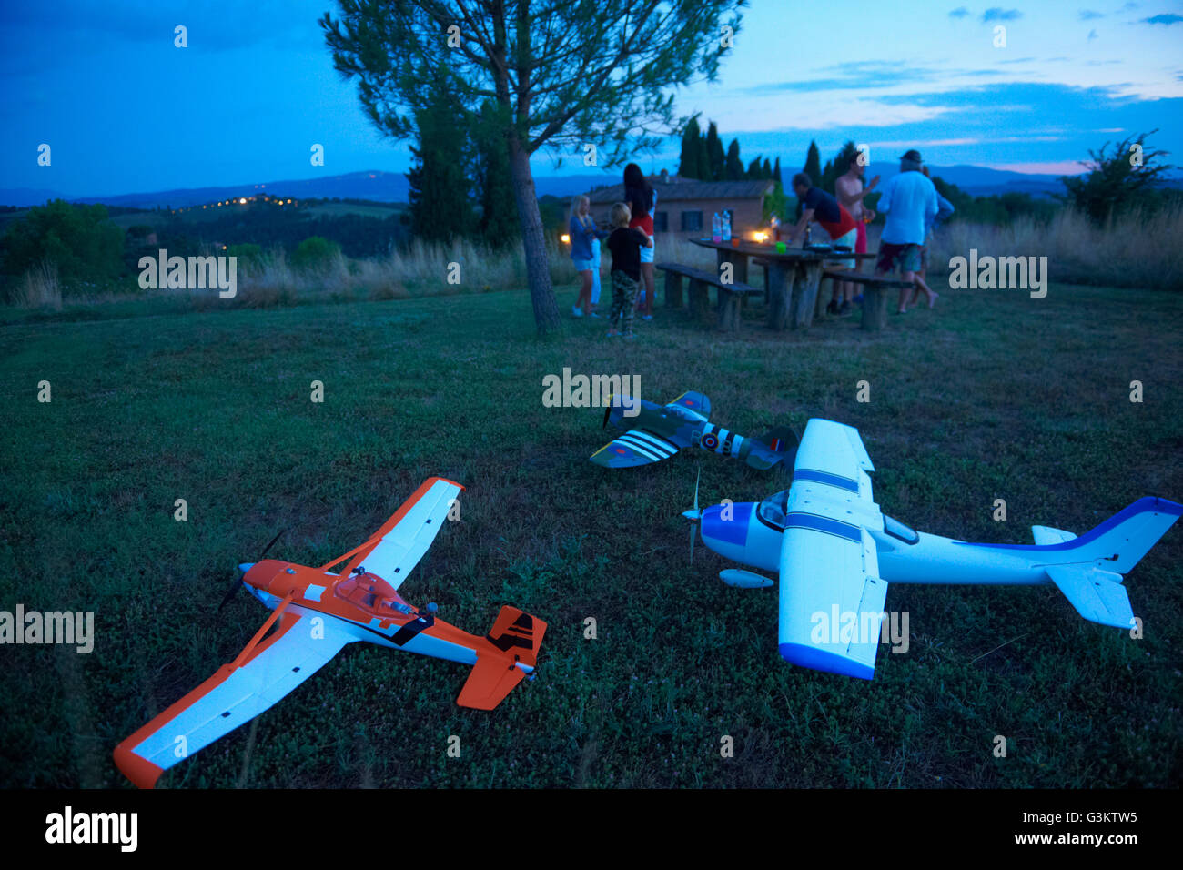 Family in field at dusk, remote control planes in foreground Stock Photo