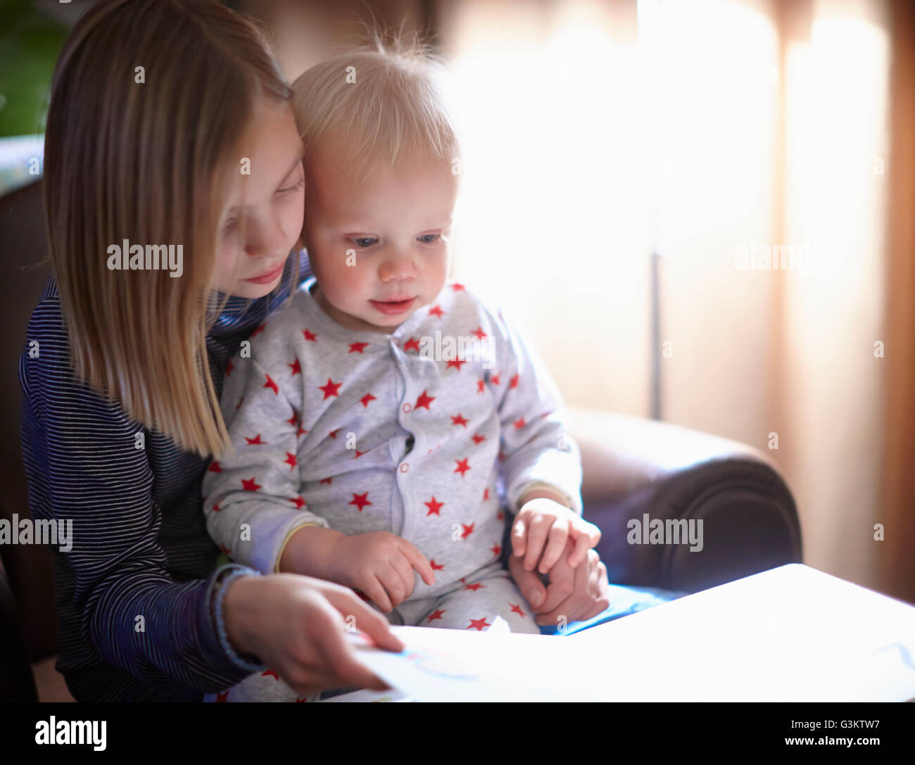 Young girl reading to baby brother Stock Photo