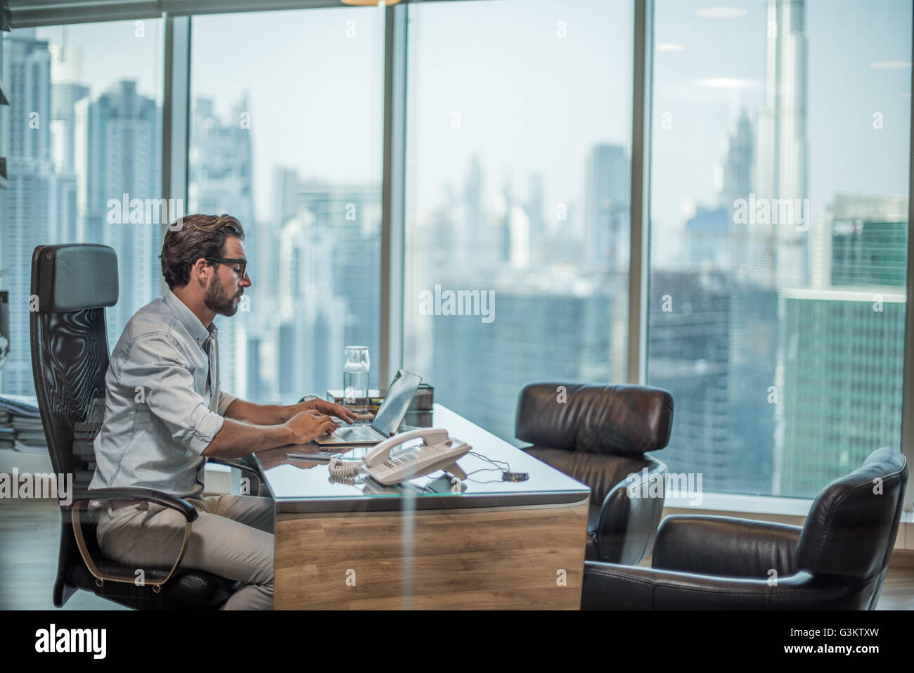 Businessman using laptop at desk with window view of Burj Khalifa