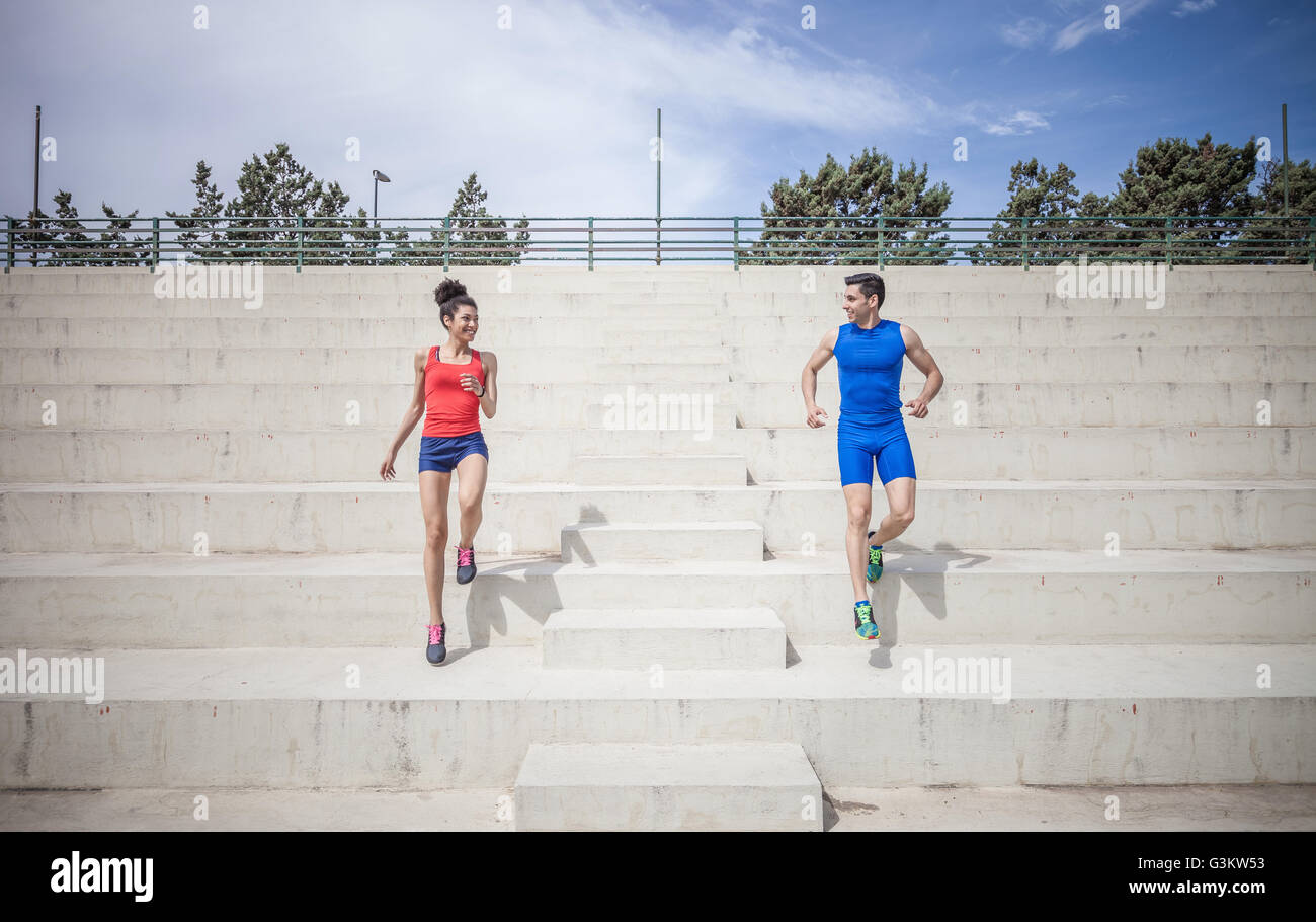 Young male and female runners moving down stairway Stock Photo