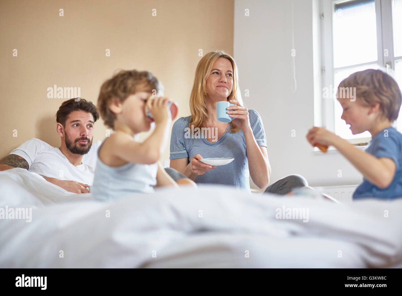 Boys having breakfast in parents bed Stock Photo