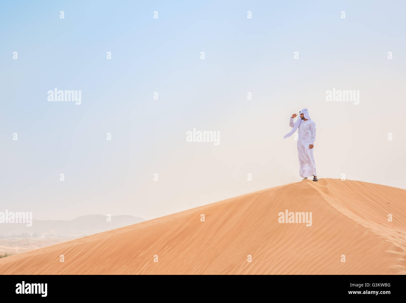 Middle eastern man wearing traditional clothes looking out from desert ...