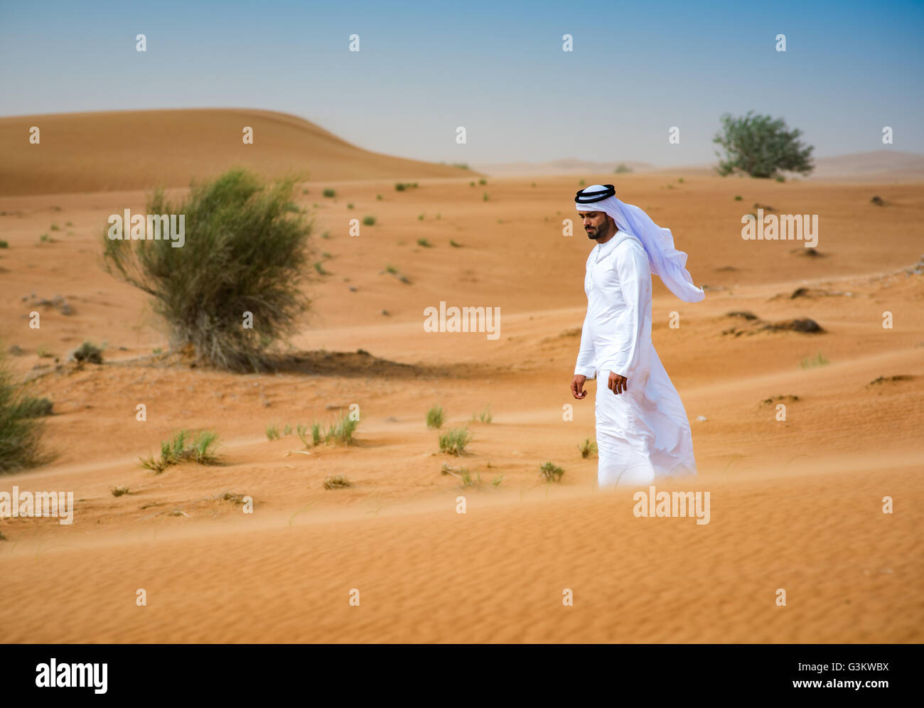 Middle eastern man wearing traditional clothes walking in desert, Dubai ...